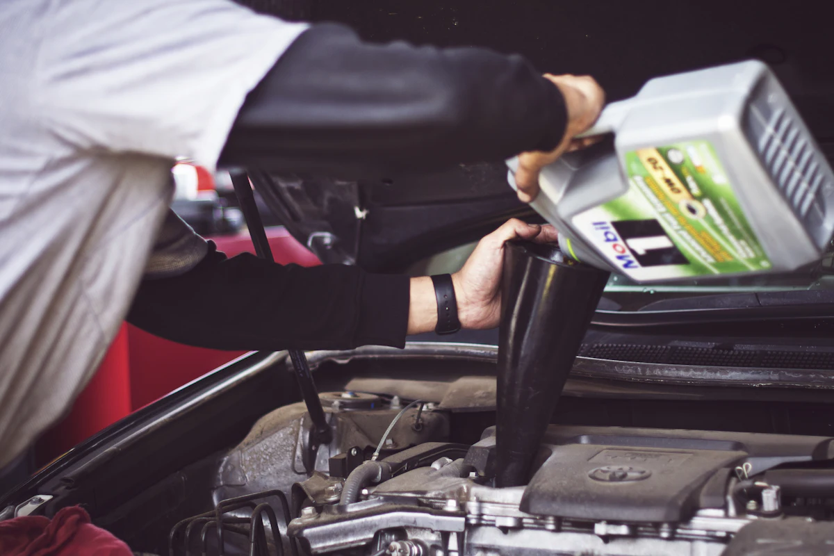 Mechanic topping up engine oil during a service in a workshop