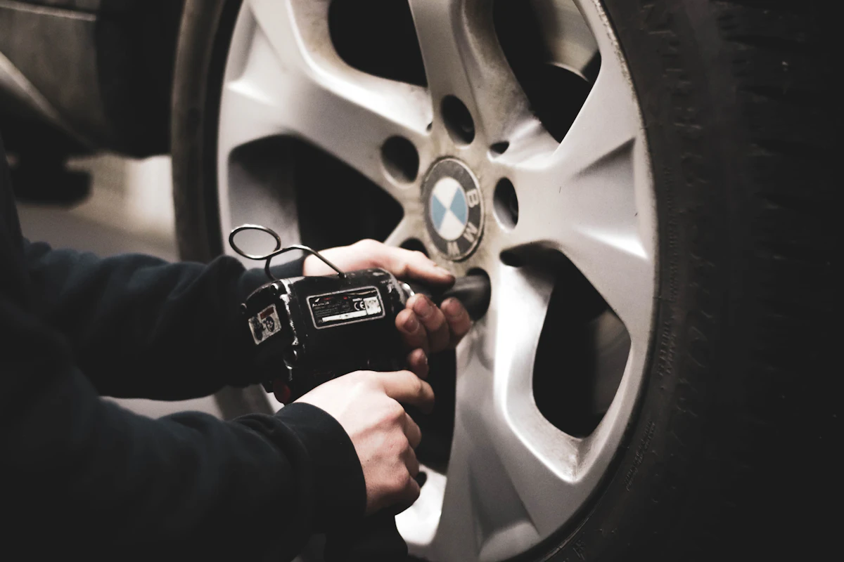 Technician checking a car wheel with an impact wrench in a garage bay