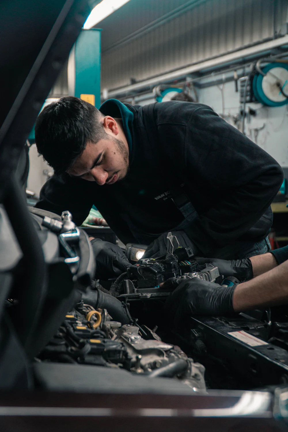 Technician working on a car engine in a UK independent garage workshop